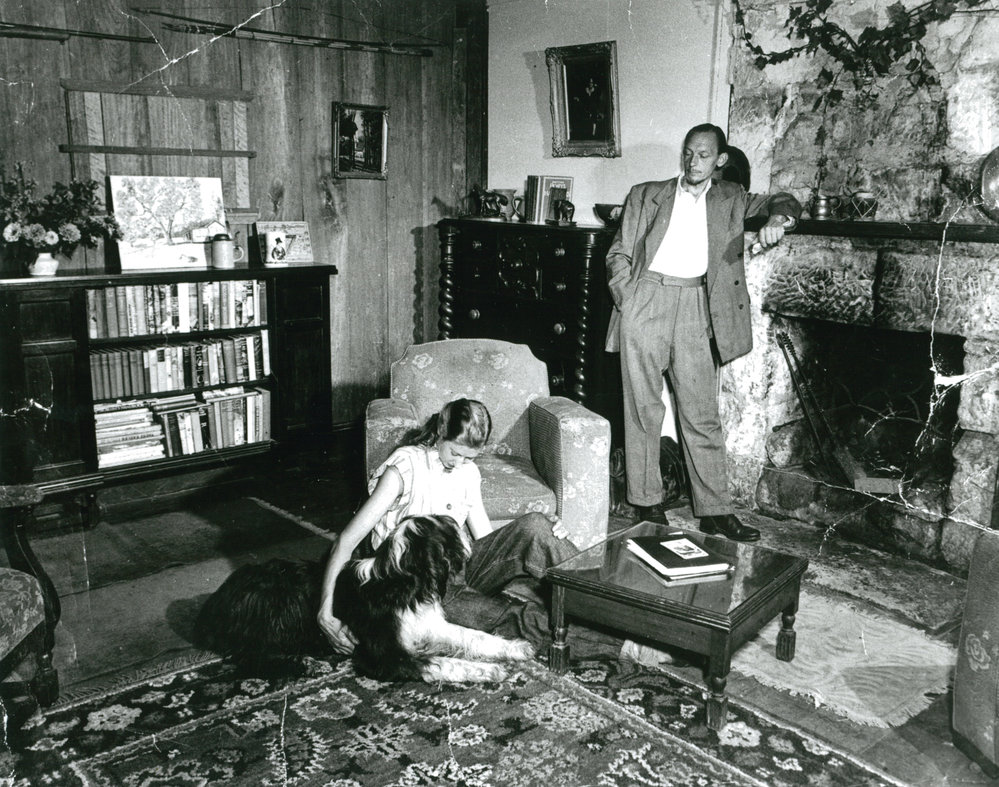 Man and woman with a dog in a lounge room.