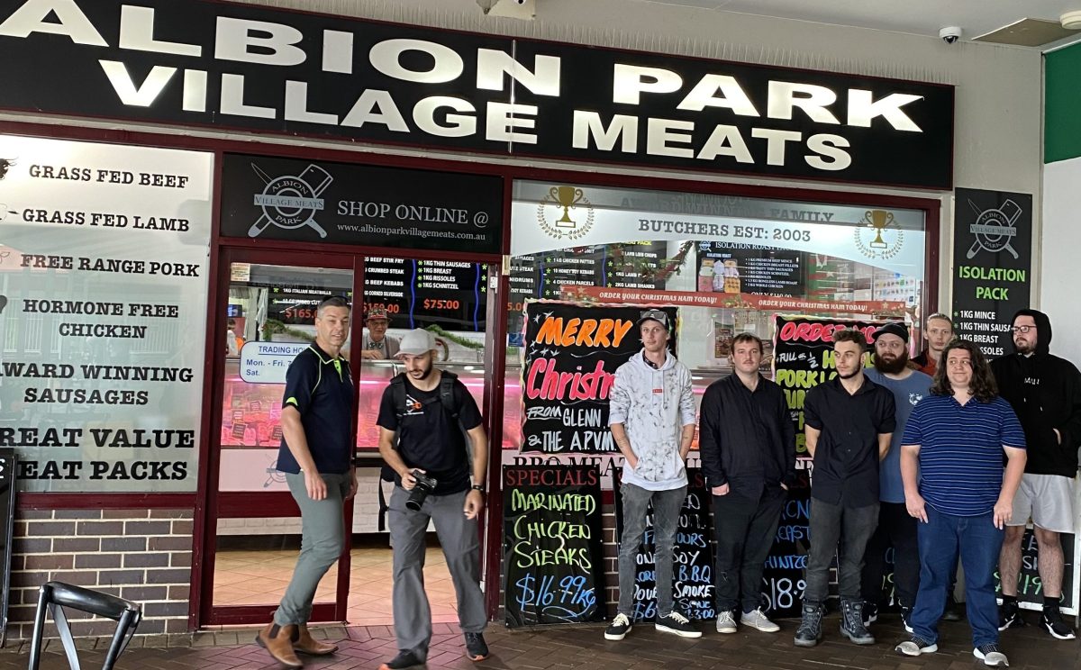 A group of students in front of a butcher's shop.