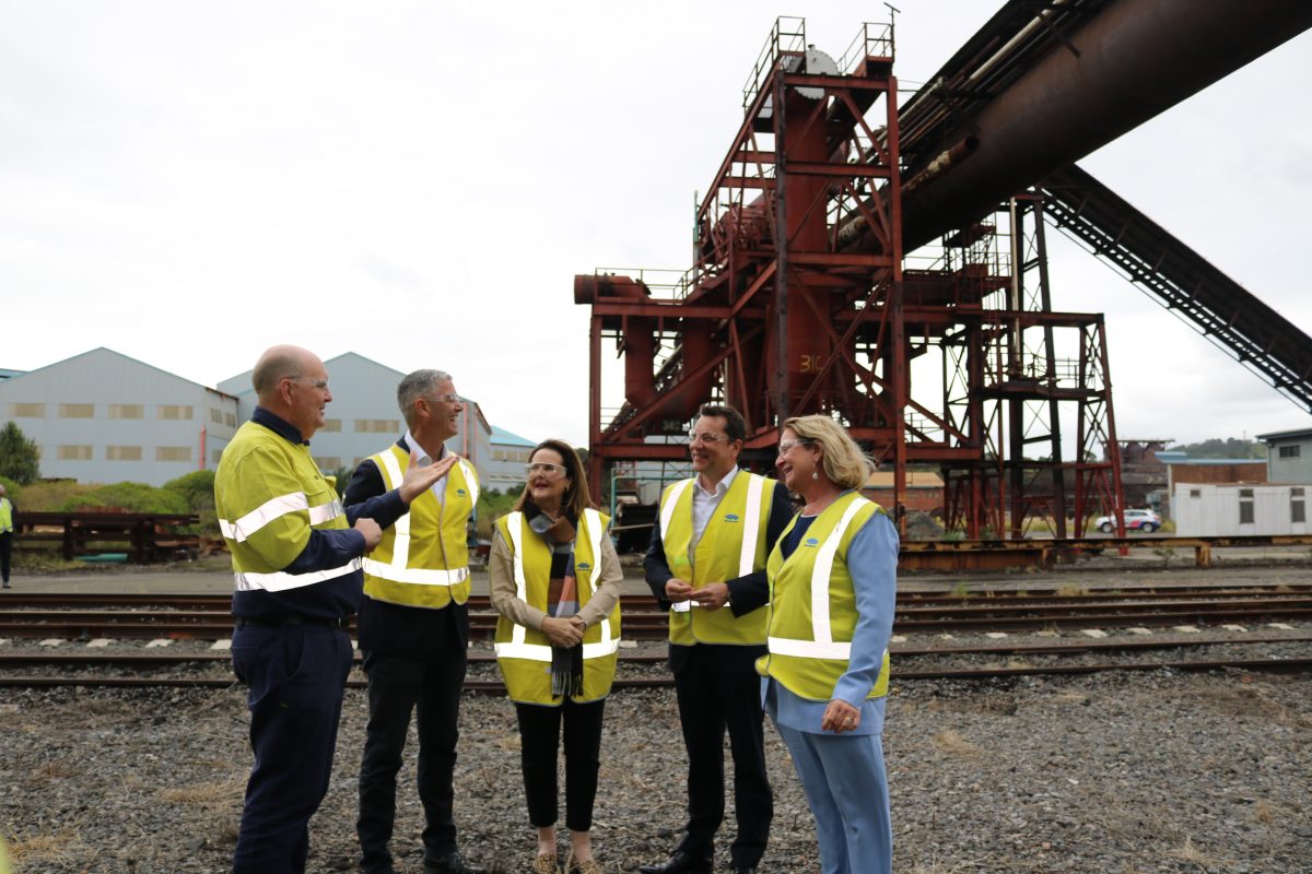 Five people standing in an industrial area.