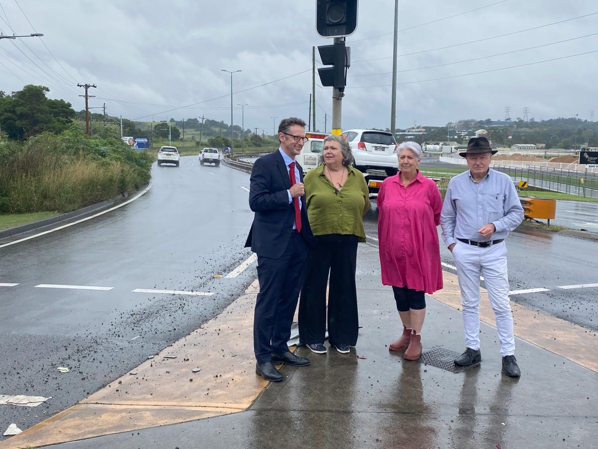 Four people standing next to a road.