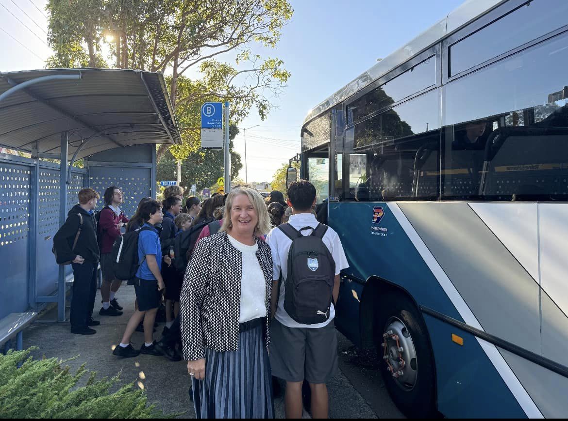 Woman in front of school kids getting on a bus.