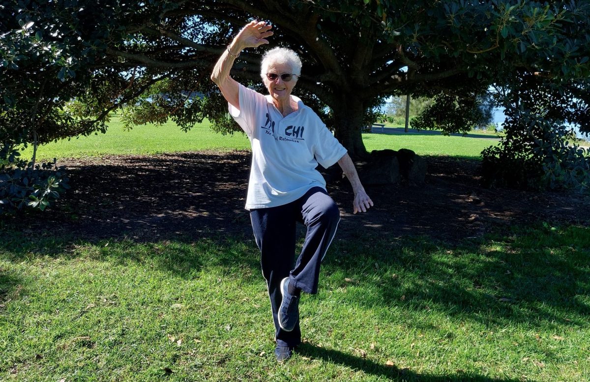 Woman doing tai chi under a tree.