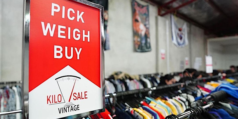Sign that reads pick weigh buy Kilo Sale with racks of clothing