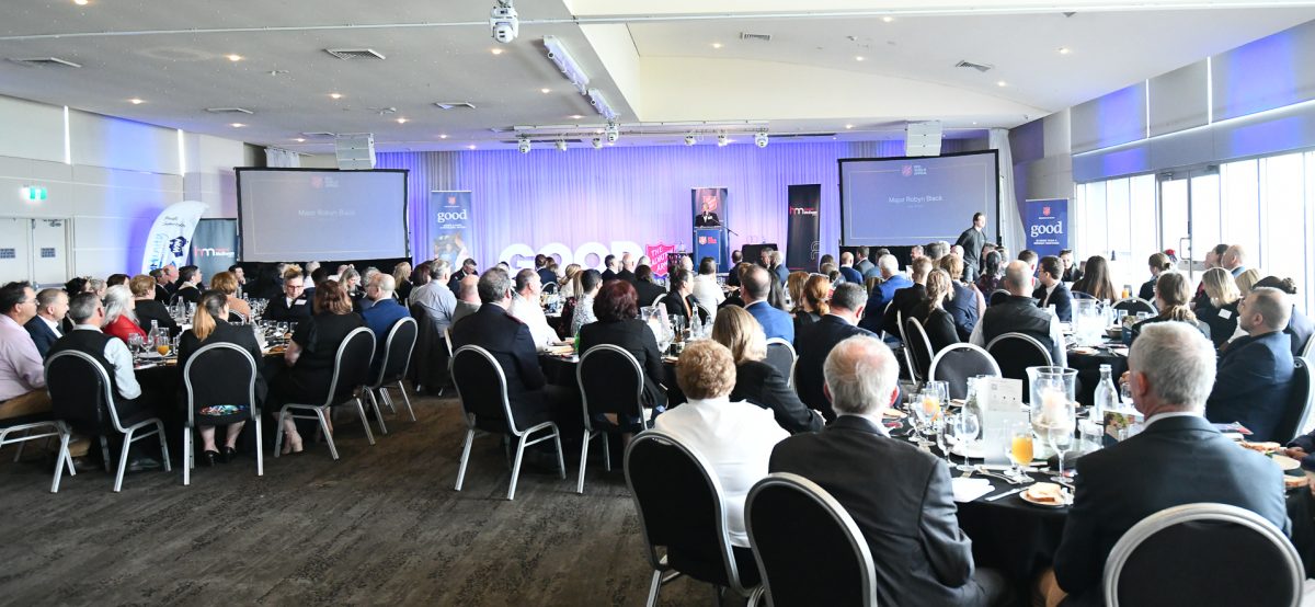 People sitting at tables listening to a speaker.