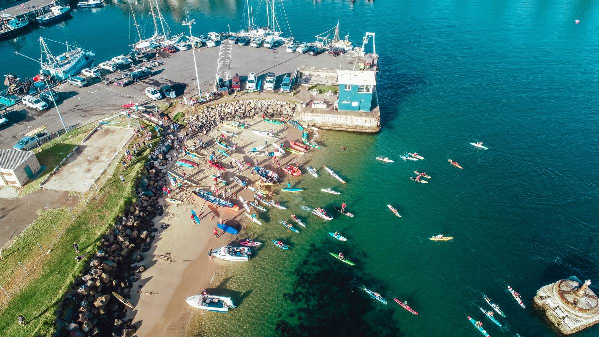 Aerial shot of paddleboarders leaving harbour.