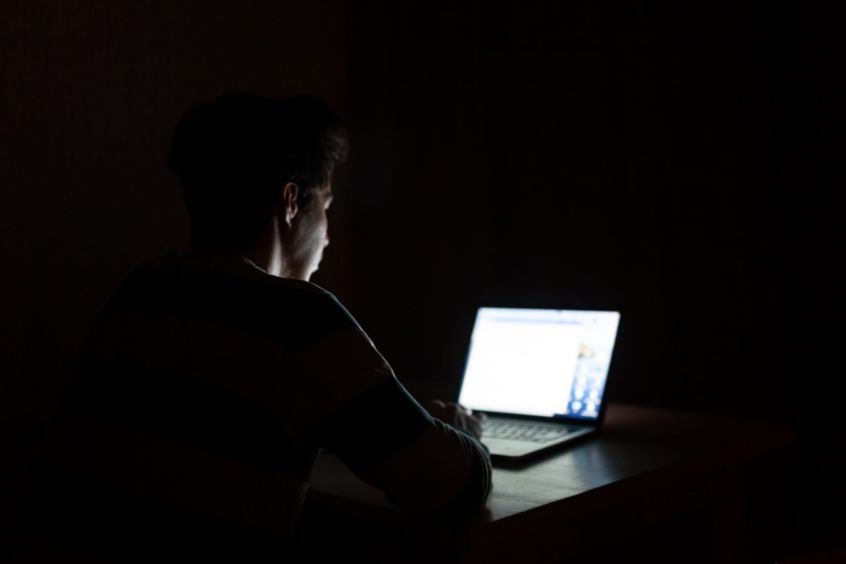 Teenager at a computer in the dark.