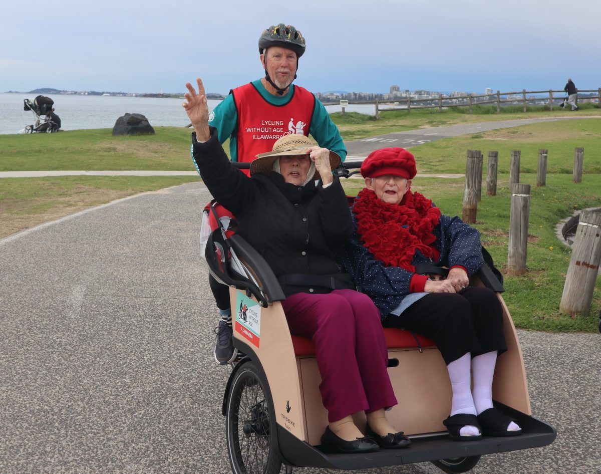 Two women on a rickshaw with a man.