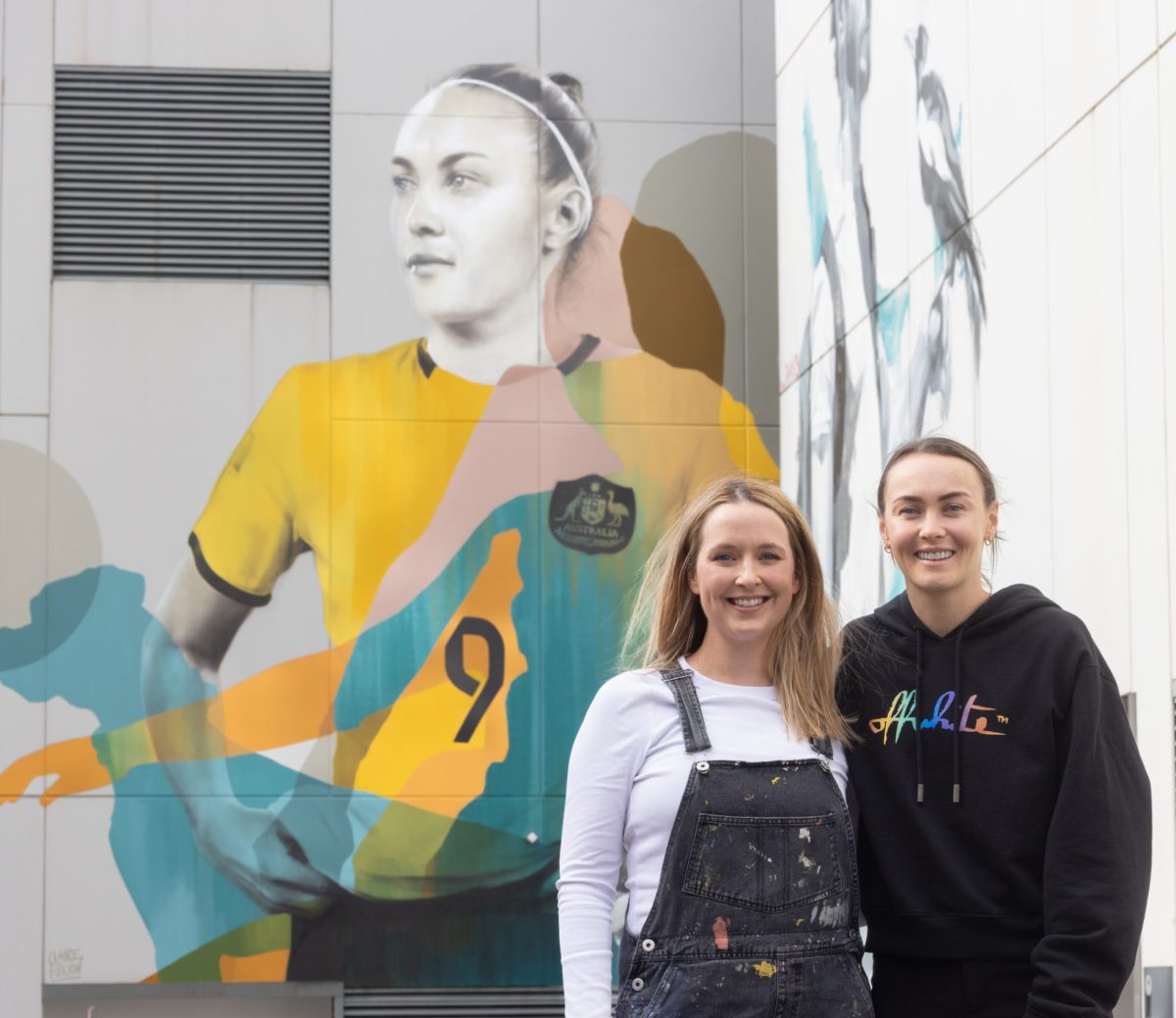 Two women standing in in front of a mural.