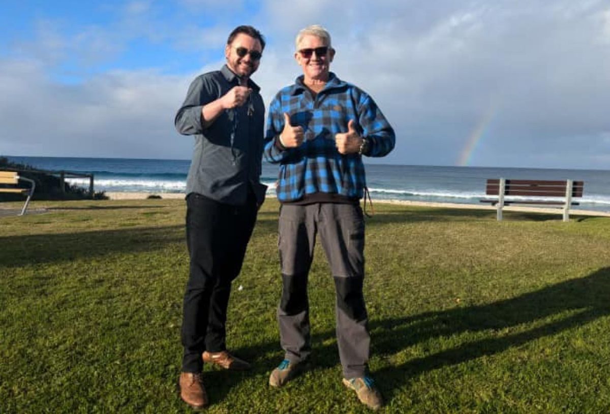 two men standing on grassy beachside area