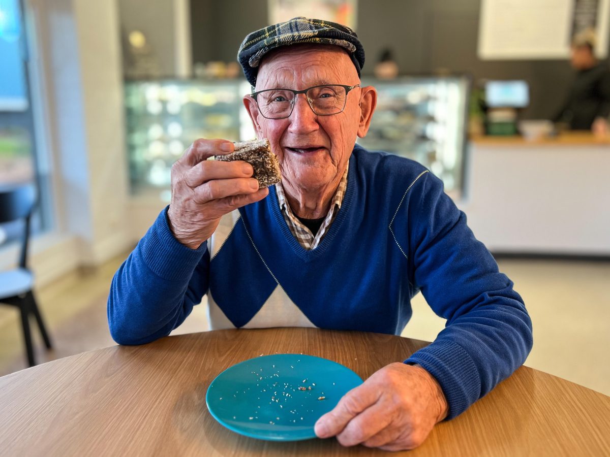 Old man eating a lamington.