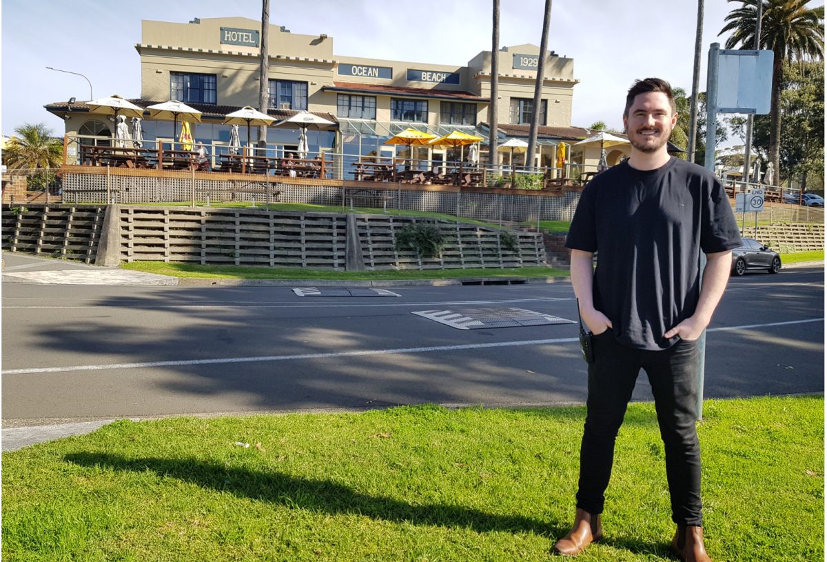 man standing across the road from a beachside pub