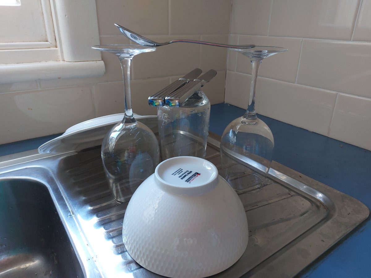 Washed up plates and cutlery on a sink.