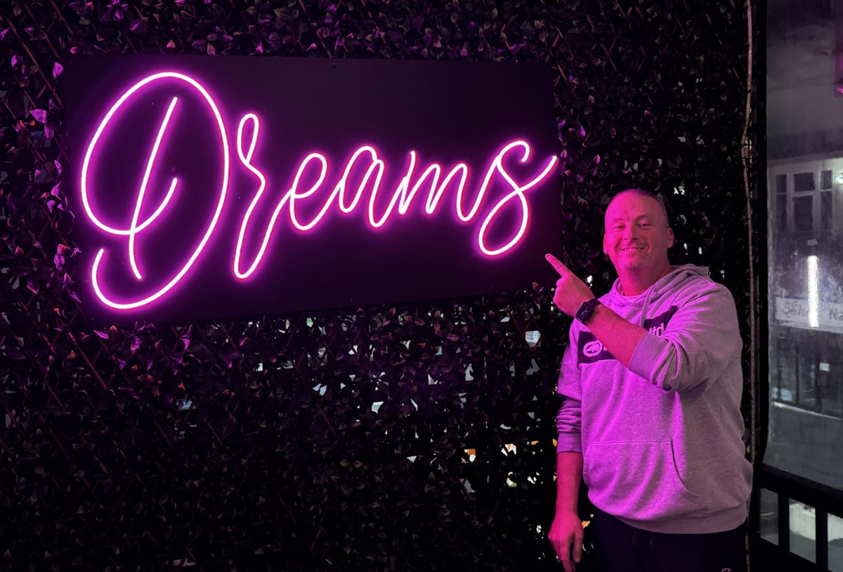 man in front of neon restaurant sign