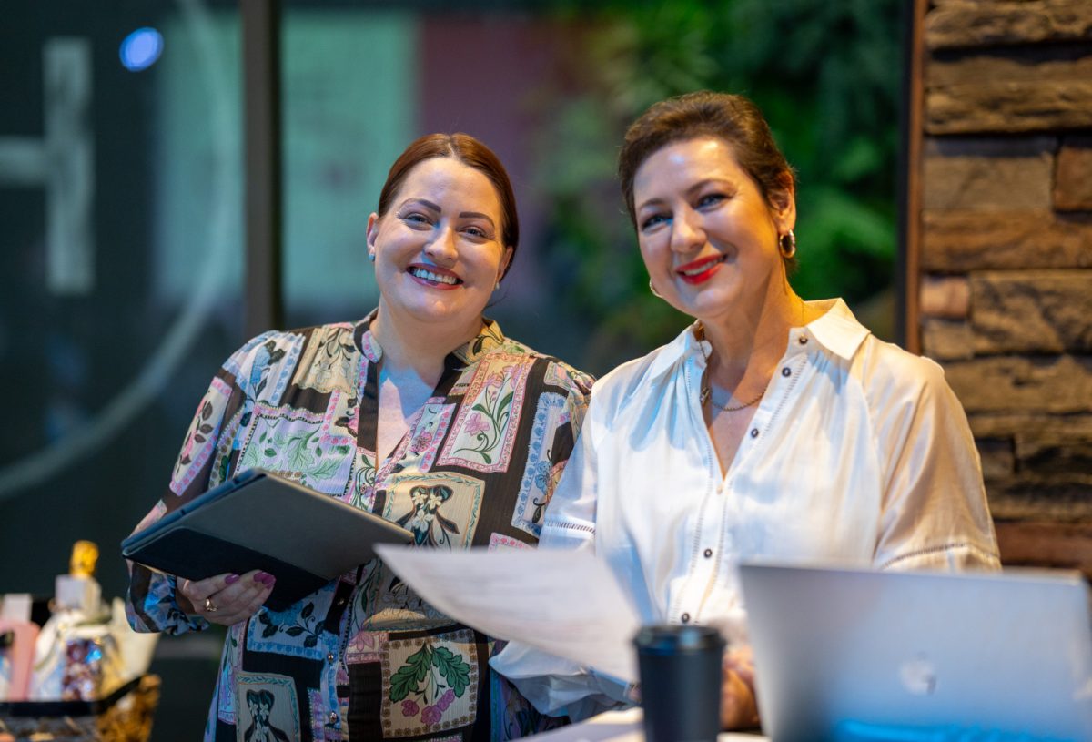 two smiling women holding documents