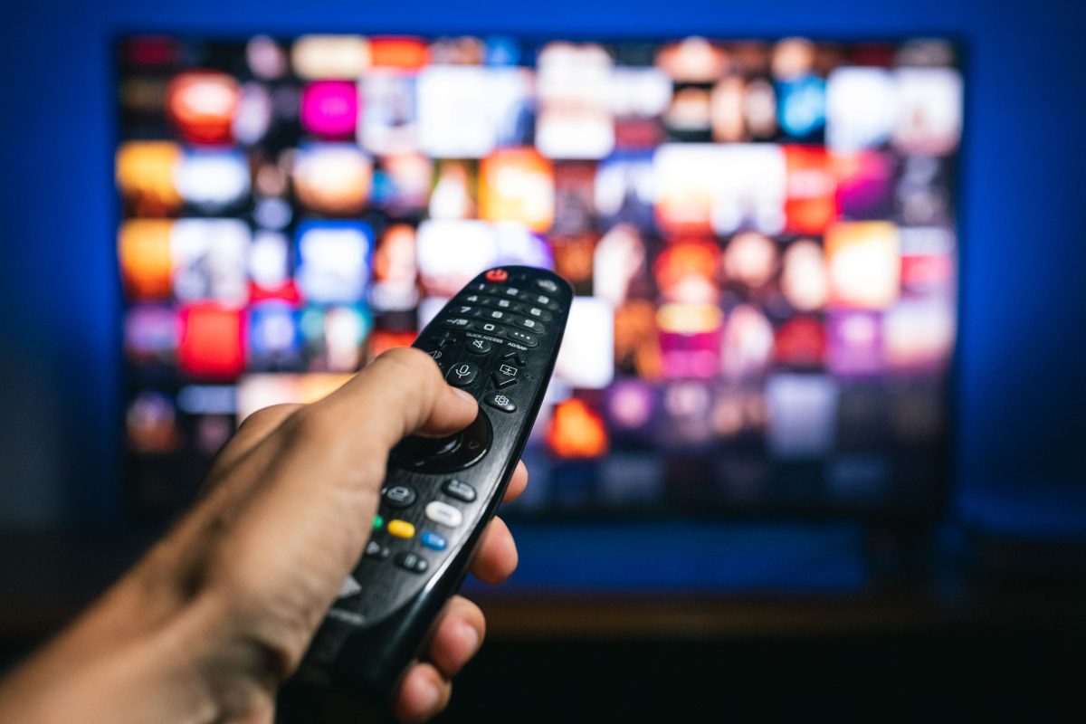Person pointing remote control at a TV.