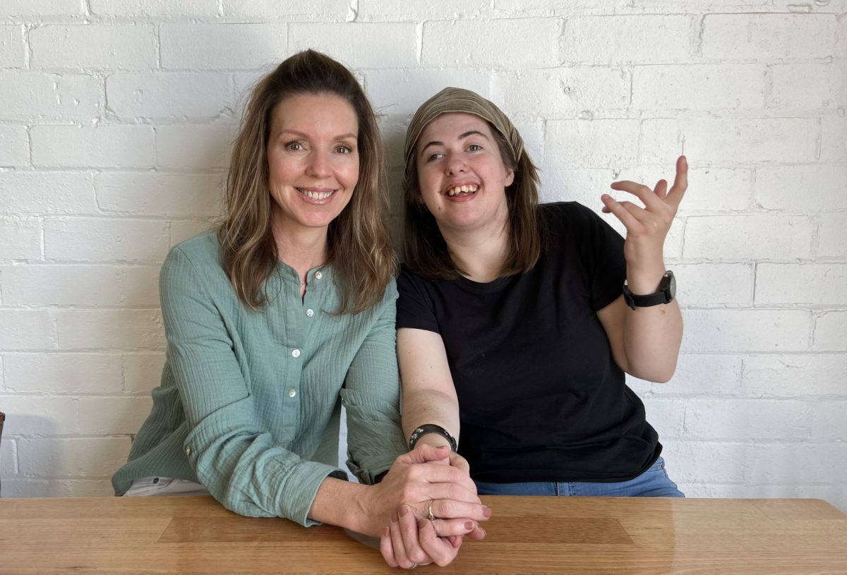 two women smiling and holding hands