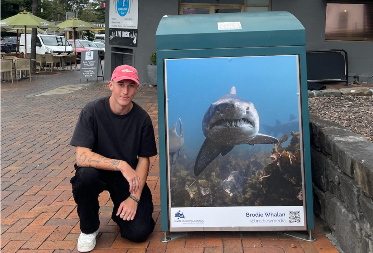 man standing next to a billboard showing a shark