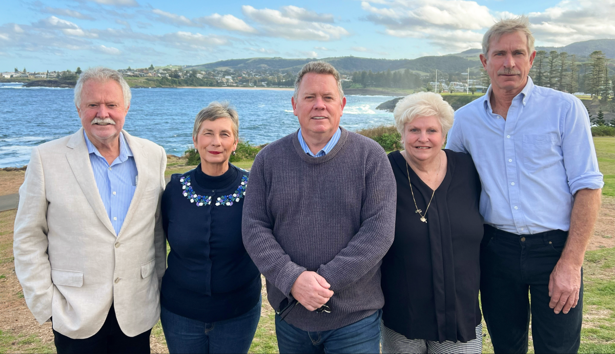 Five people standing in front of ocean