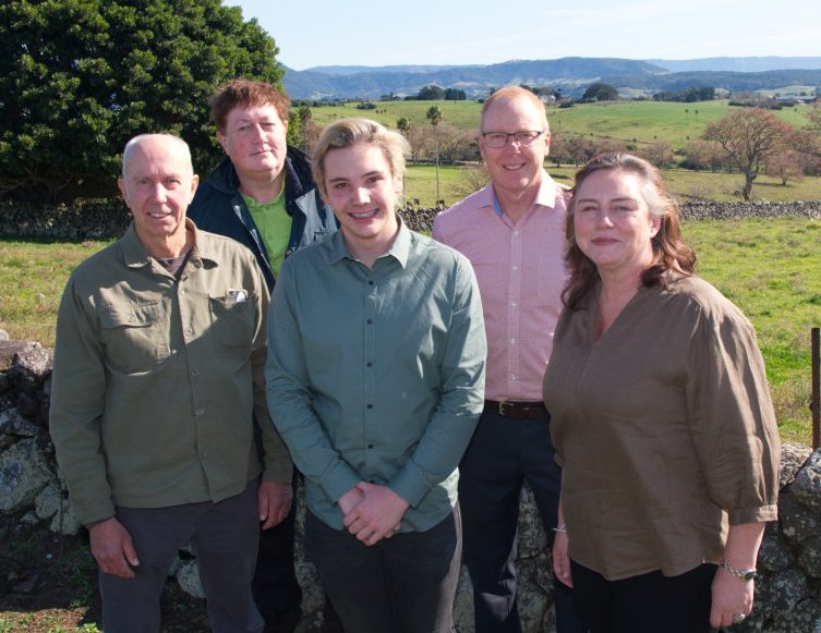 Five people in front of a stone wall.