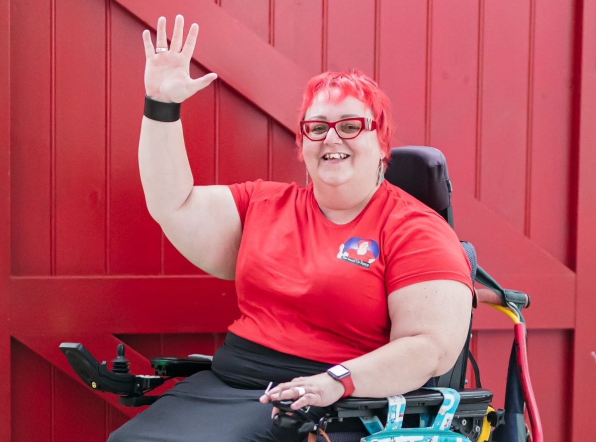 woman in a wheelchair holding her hand up