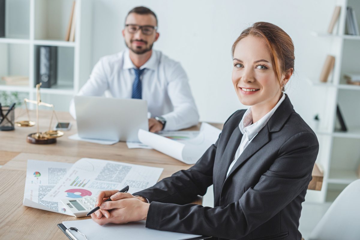 professional man and woman smiling at desk