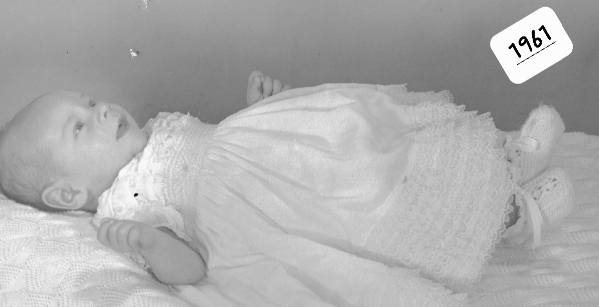 Black and white photo of a baby in a white dress