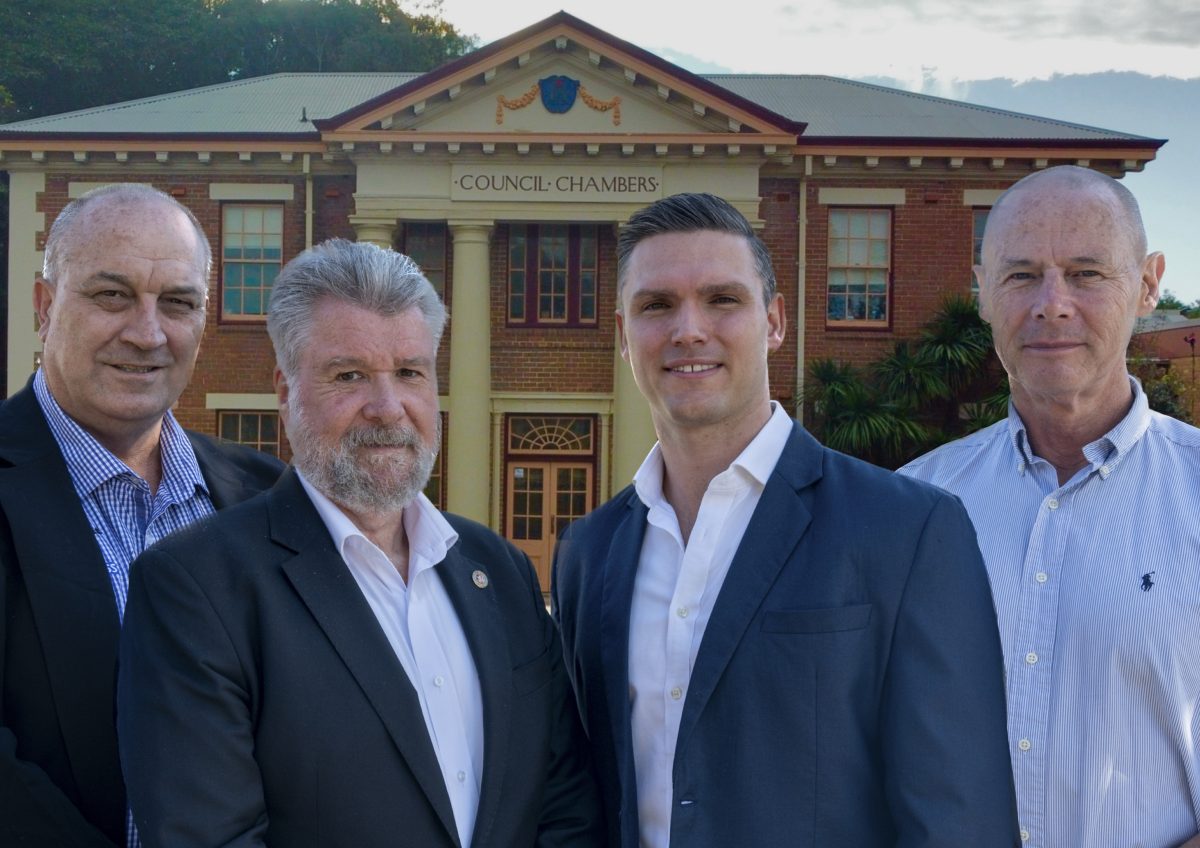 Four men in front of council chambers