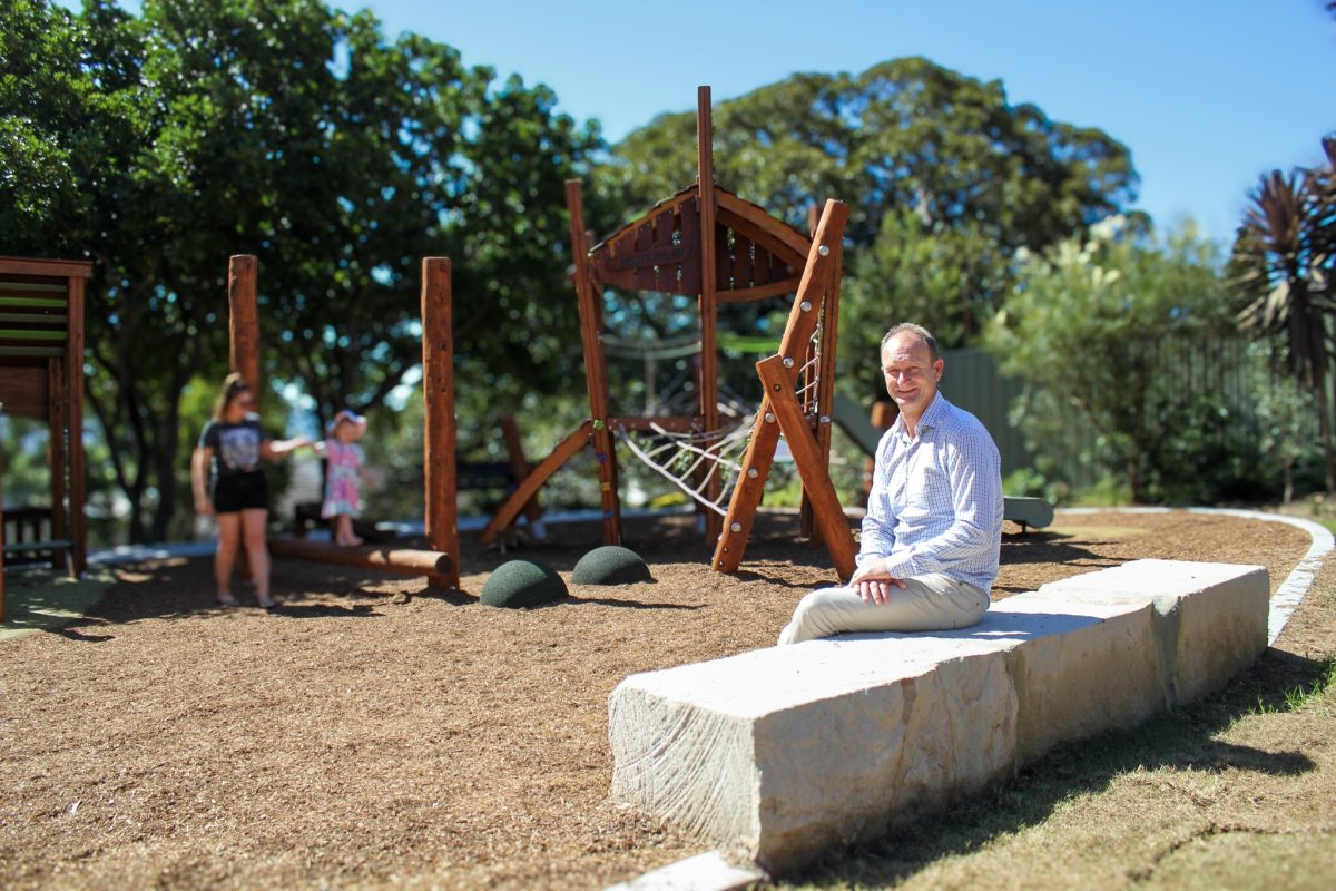 Mayor Chris Homer sitting in front of a Shellharbour playground