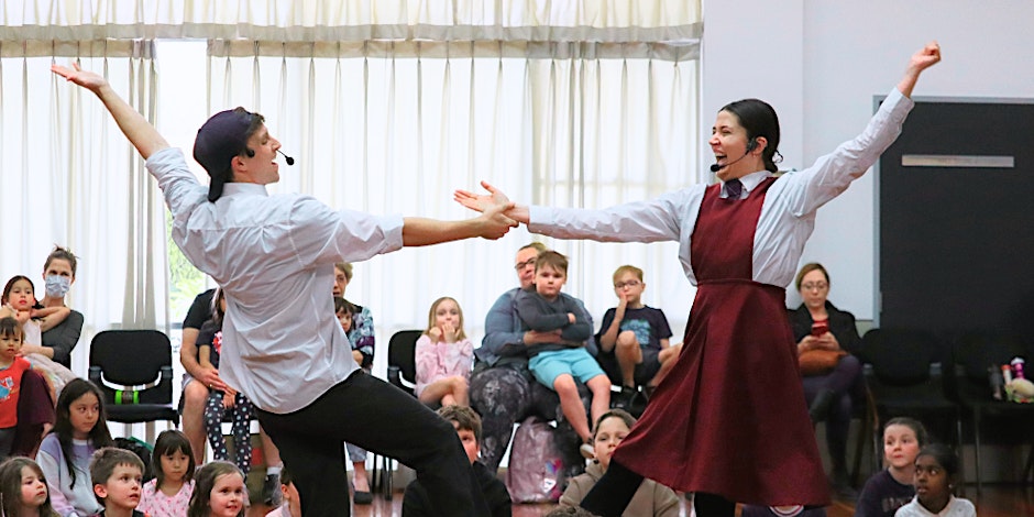 People performing in a musical in a library as children watch