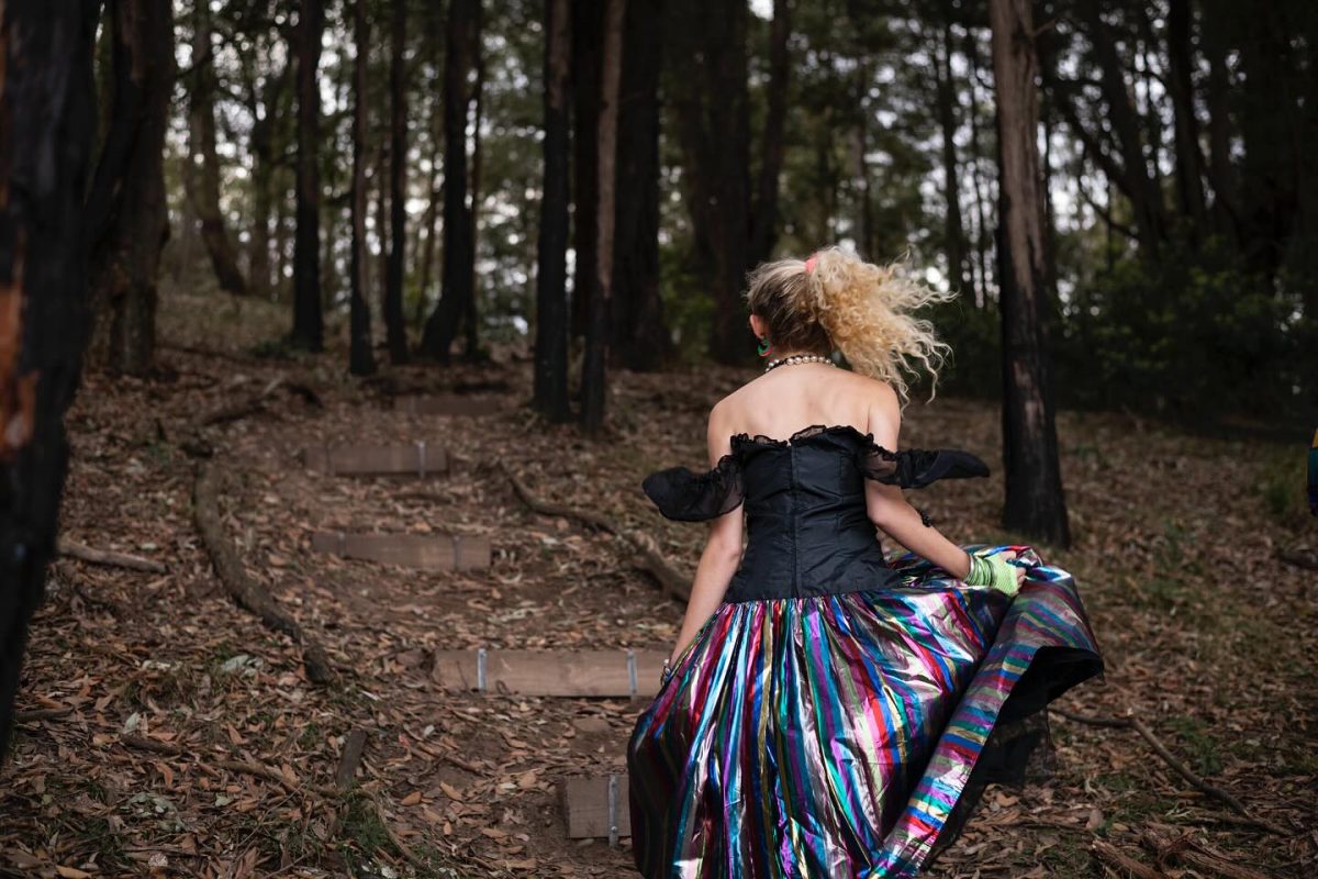 Girl dressed in 80s clothing runs through the bush