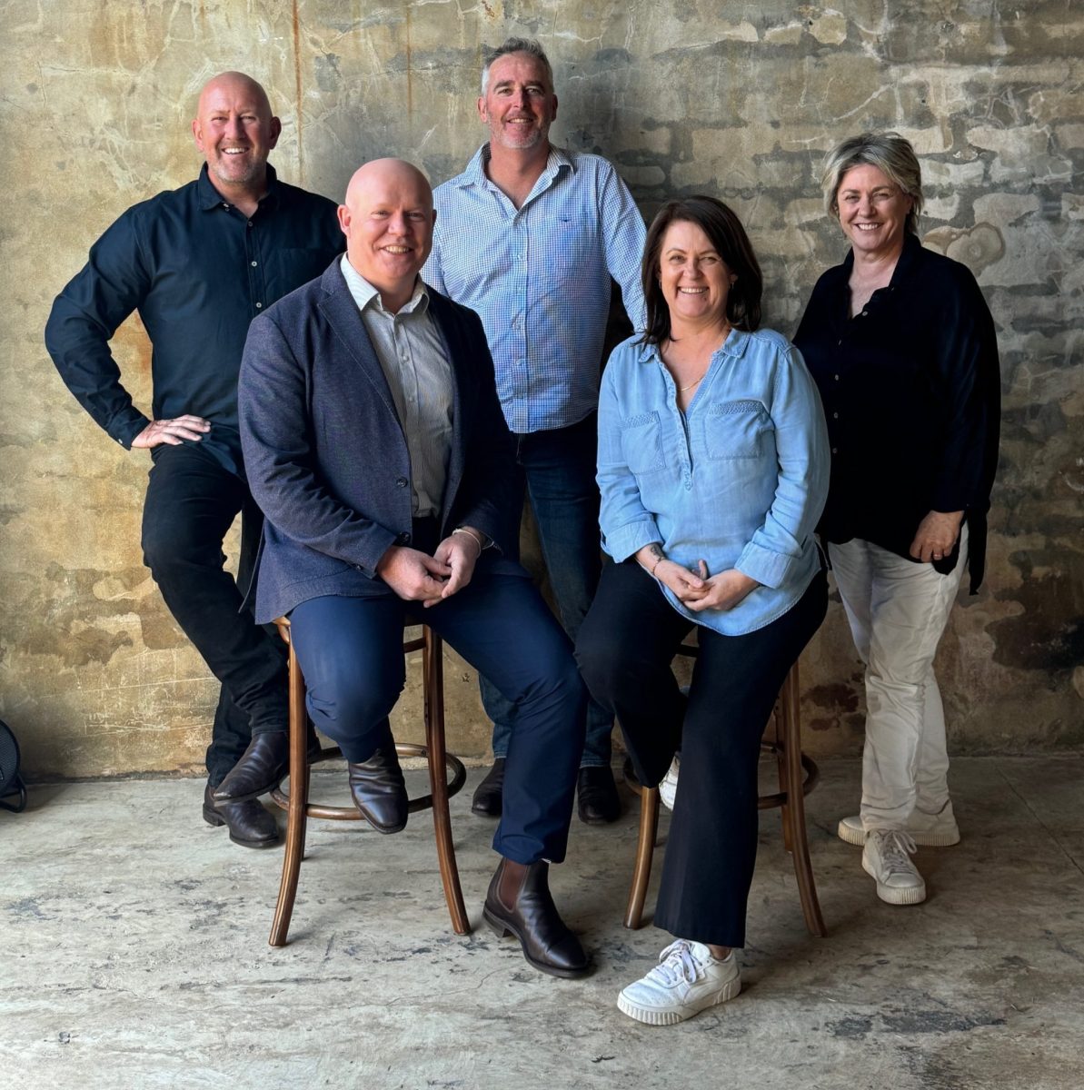 Five people standing in front of a wall.