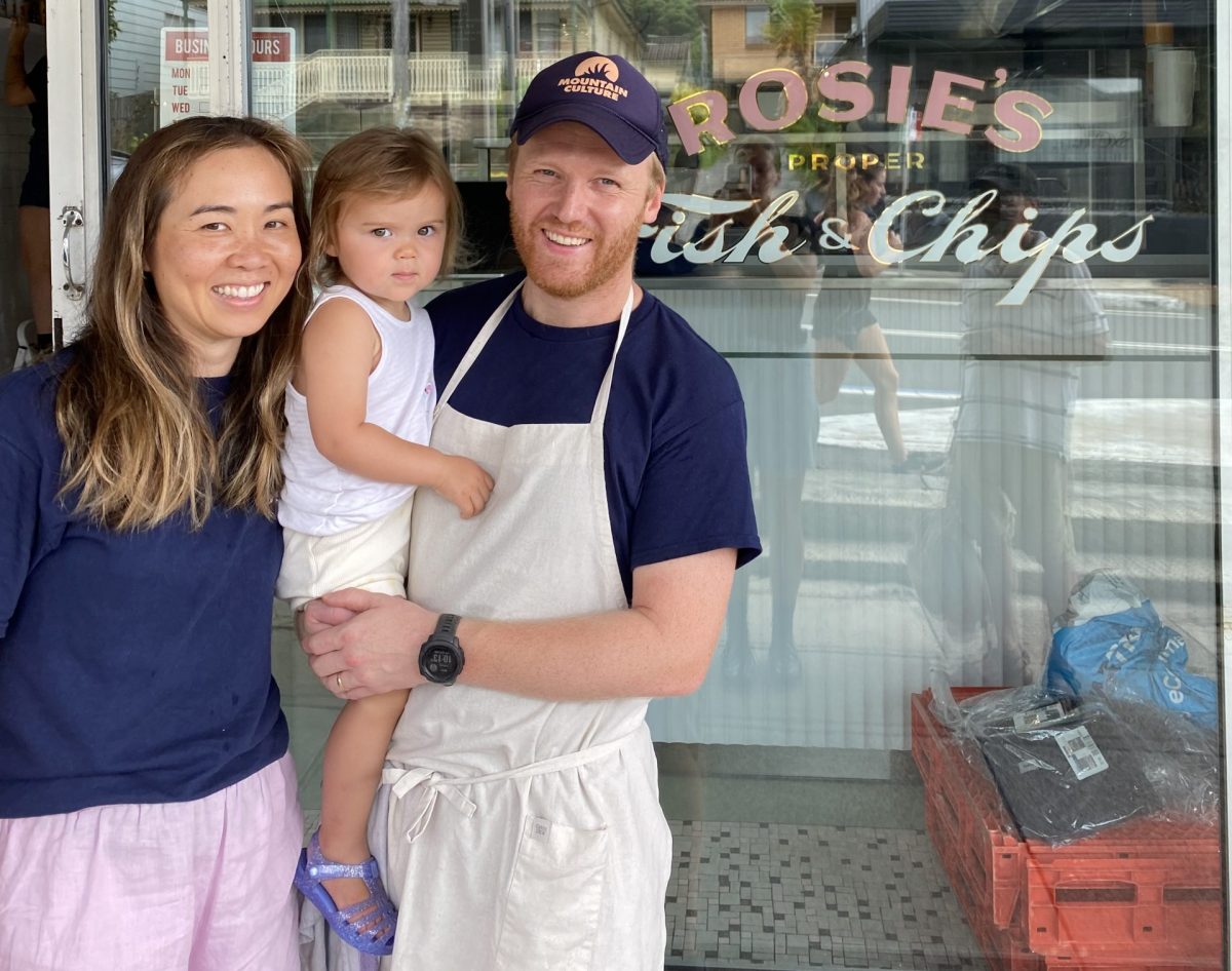 Man and woman holding child outside fish and chip shop