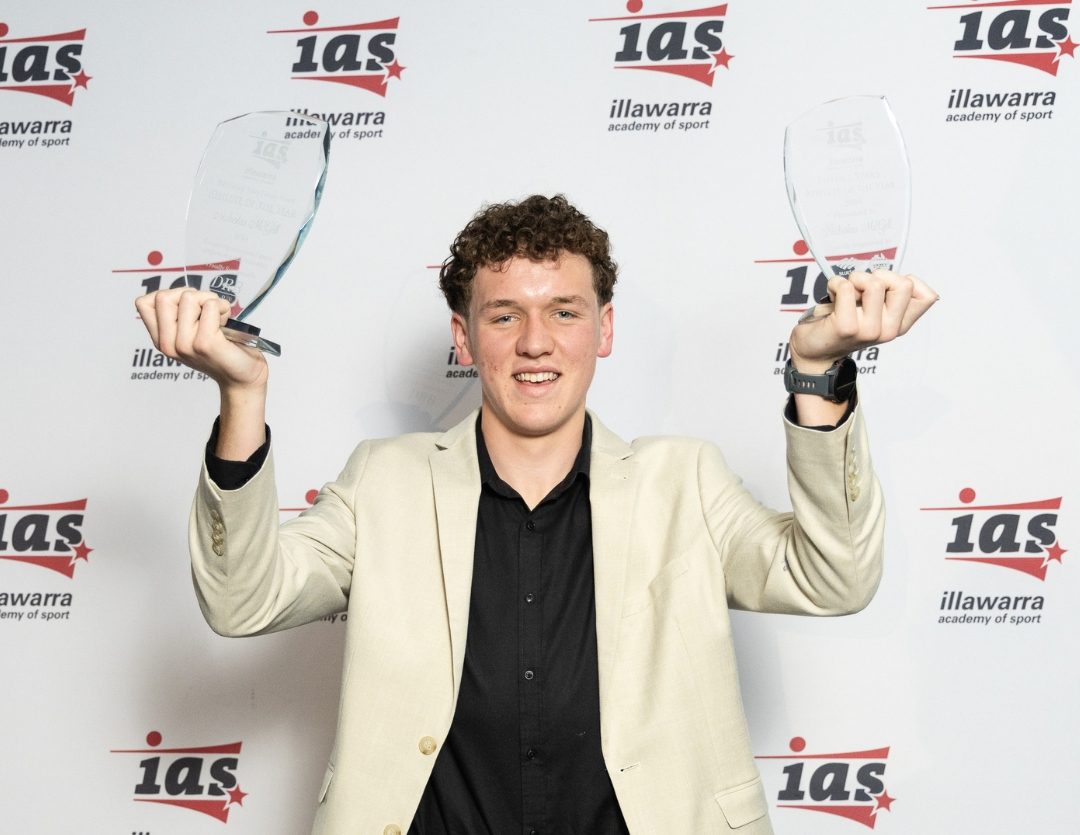 Teen holding up two trophies.