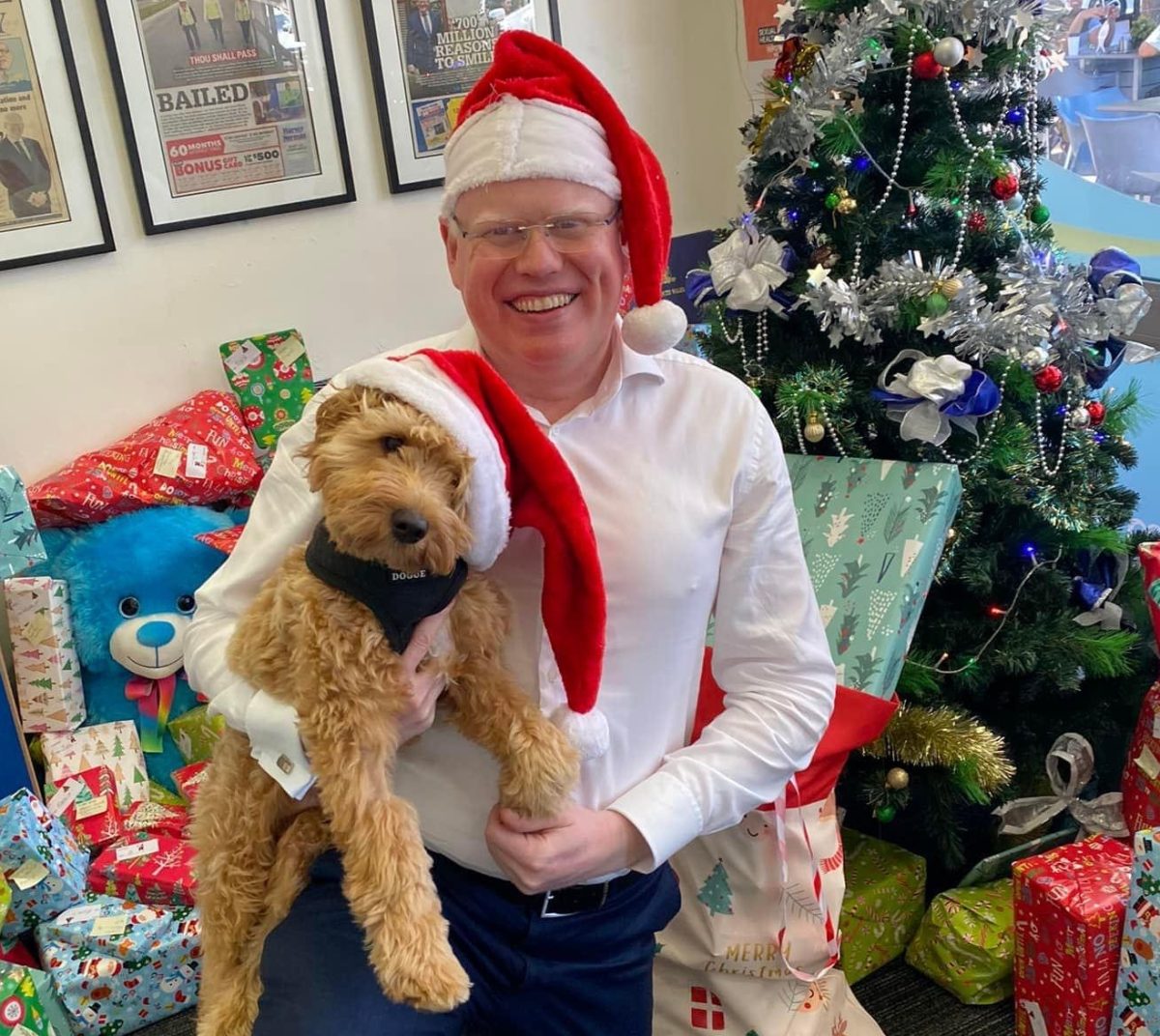 Man wearing Santa hat and holding a dog