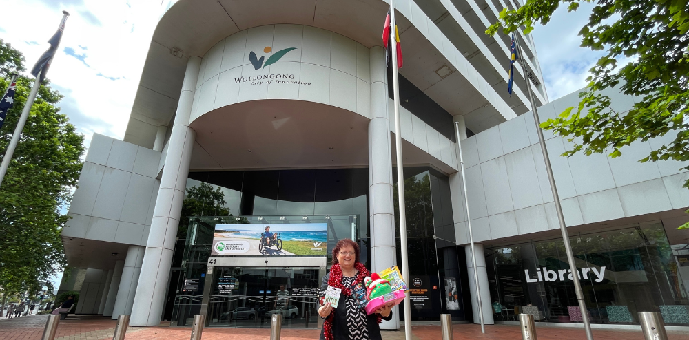 woman holding Christmas gifts in front of council building