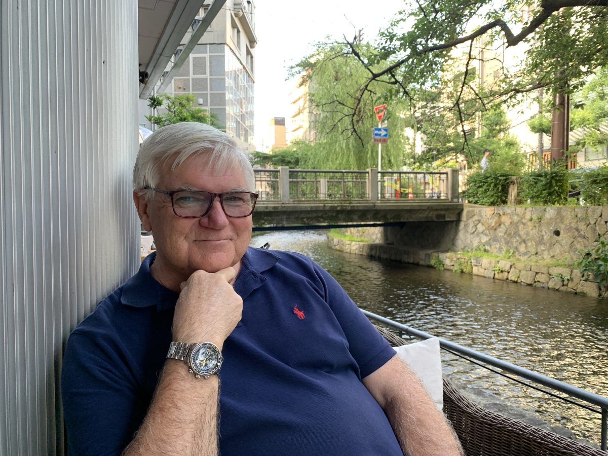 Man sitting in front of a bridge