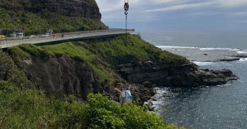 Crane carries car-size rock bags to help stabilise landslips near Sea Cliff Bridge