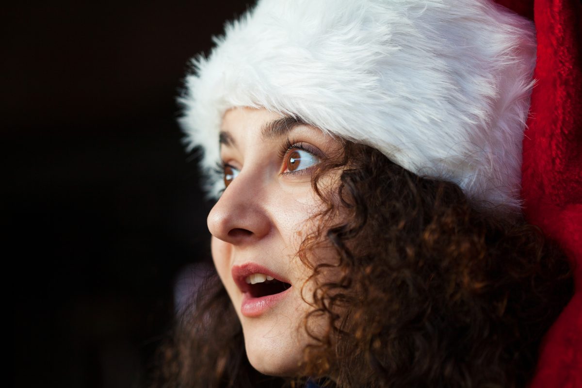 Woman sings Christmas carols in a santa hat