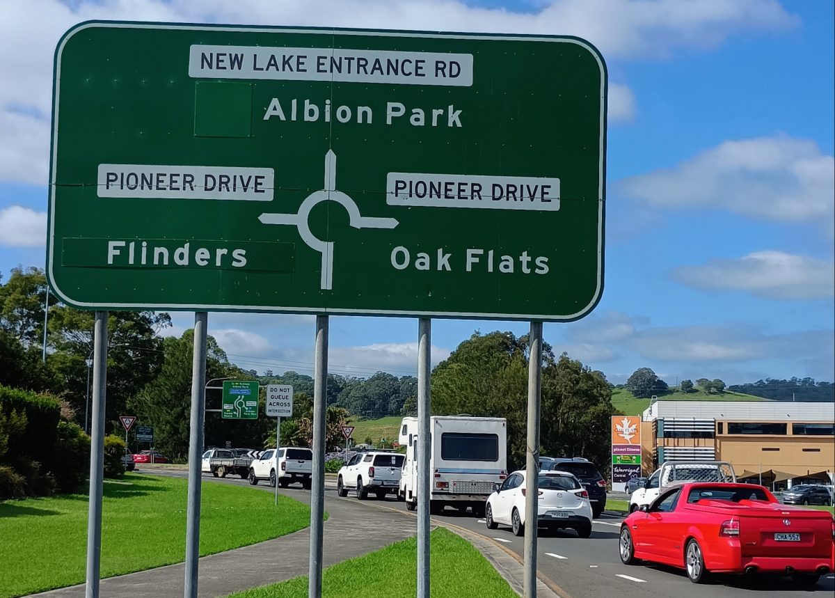 cars on the road by a round-a-about sign