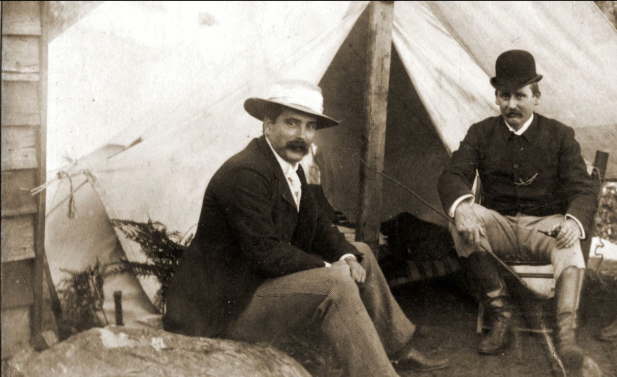 Two men sitting outside a tent