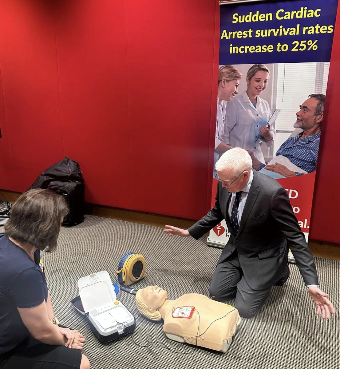 A woman demonstrating a defibrillator to a man