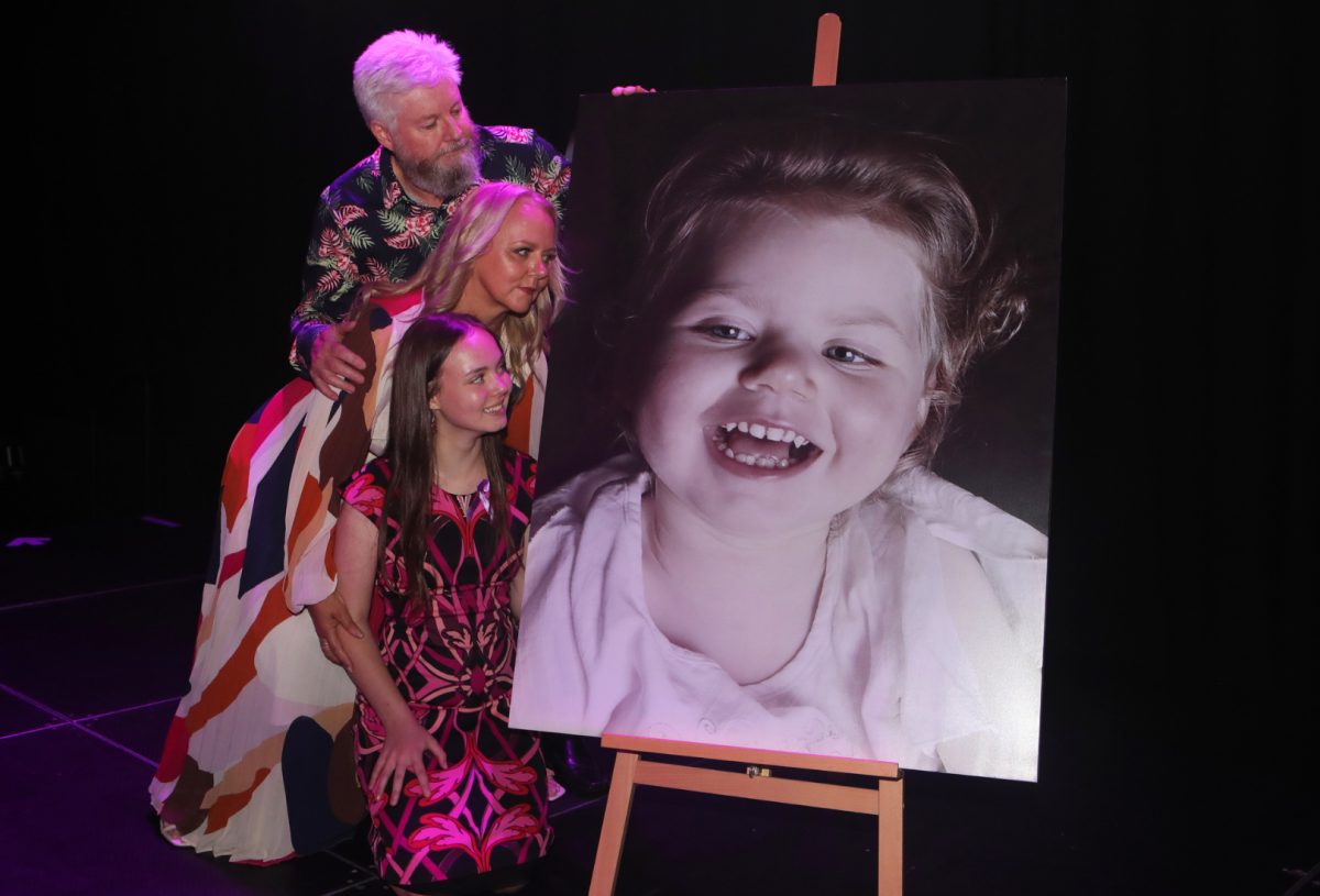 Mark, Susan and Sophie Wallis looking at a portrait of Gracie. 