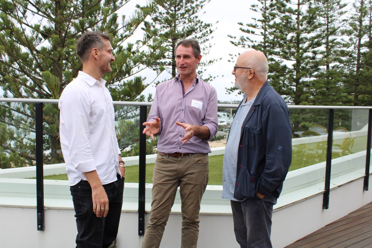 three men talking at a beachside venue