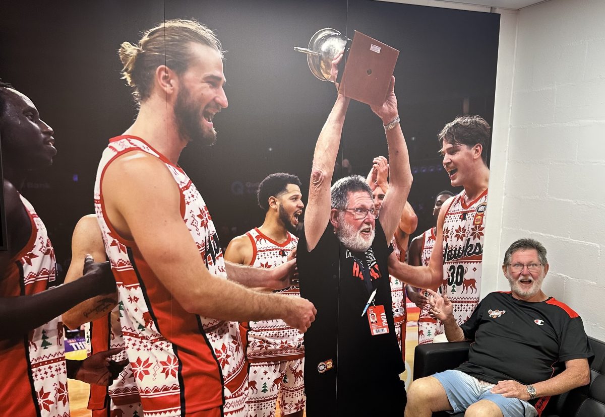 Man sitting in front of picture of basketballers