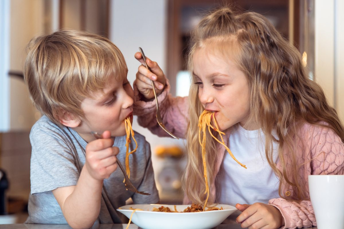 Kids eating spaghetti with bolognese sauce