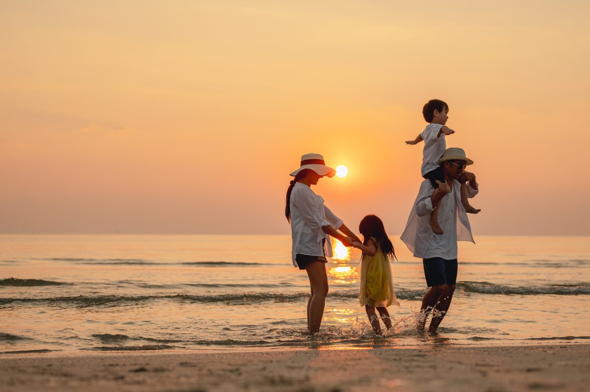 A family plays on the beach at sunset