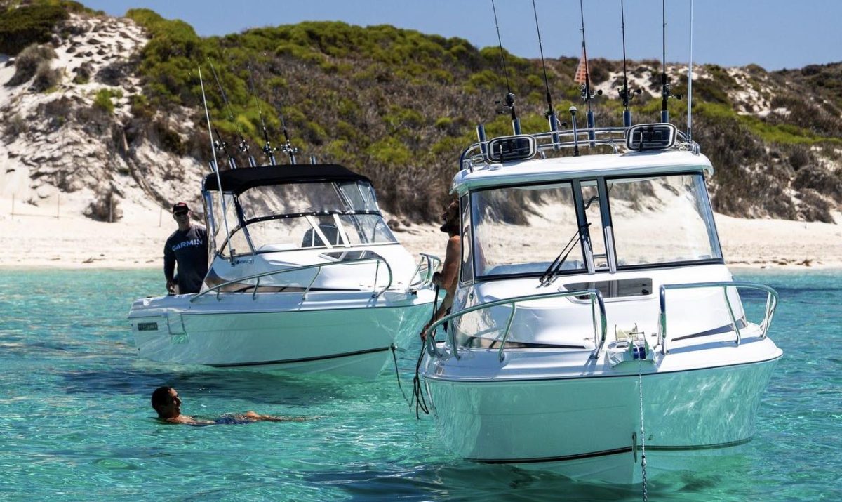 Man swims on aqua water with two boats