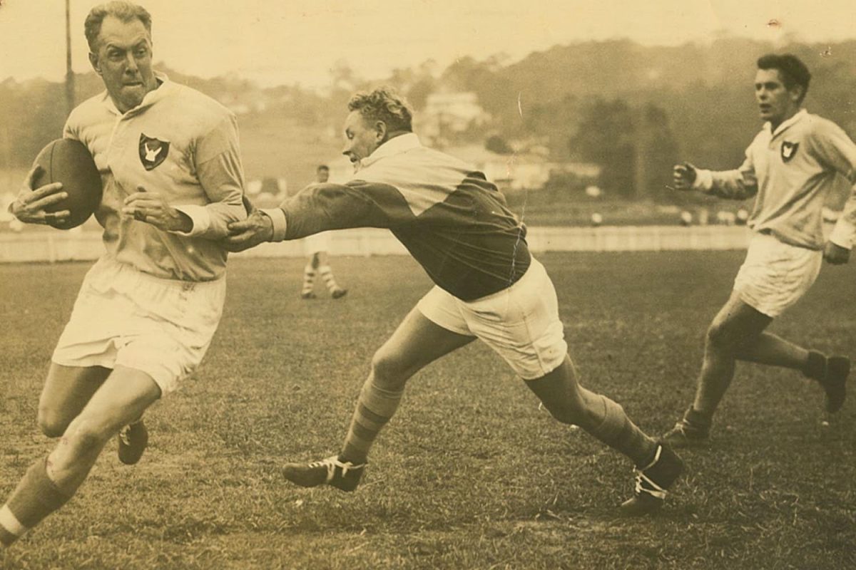 Old photo of three men playing rugby