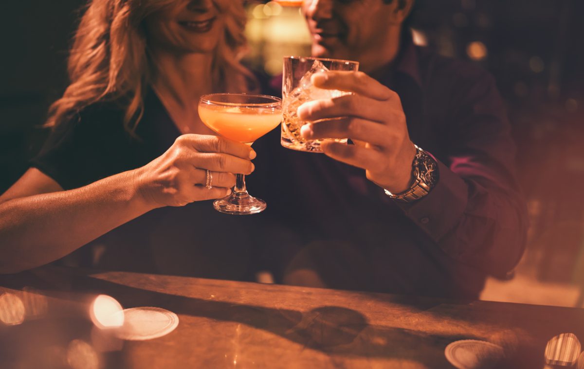 Close-up of mature couple toasting with drinks at bar