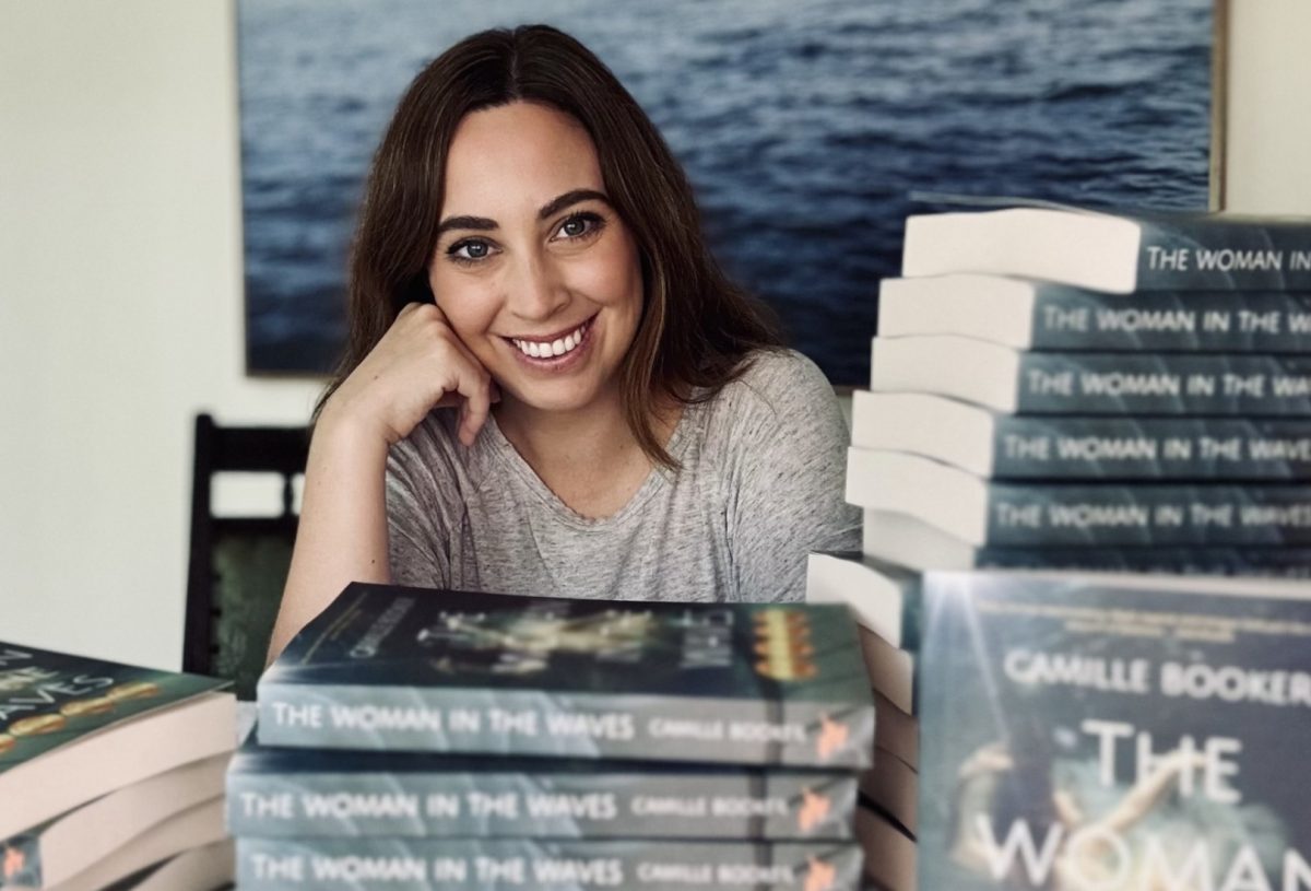 a smiling woman with books on a table